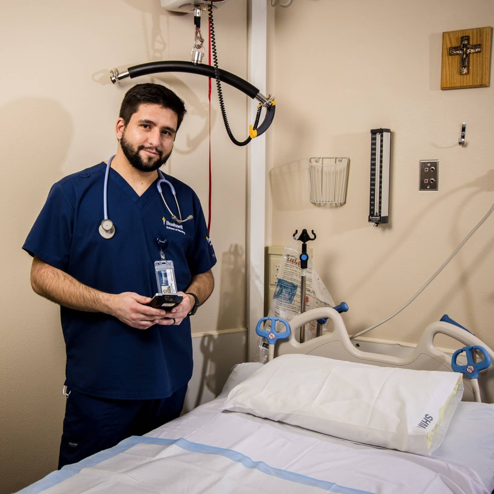 Nursing student in scrubs in front of bed