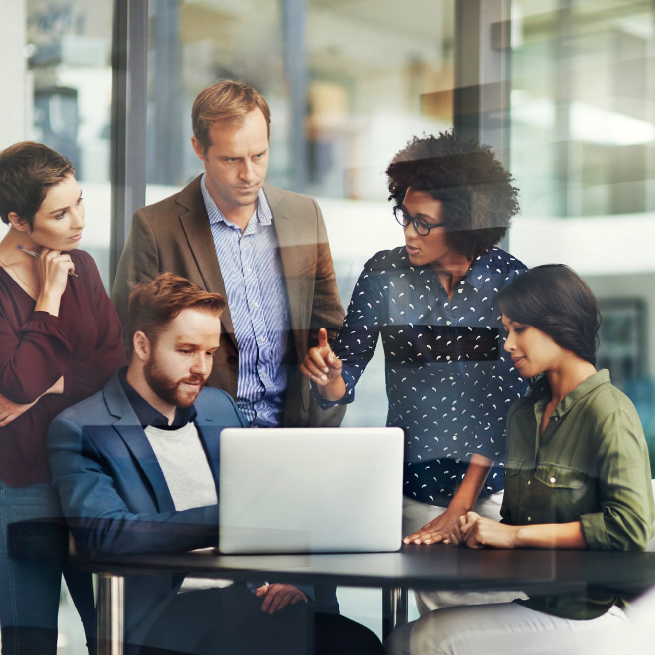 Shot of a group of colleagues using a laptop together at work