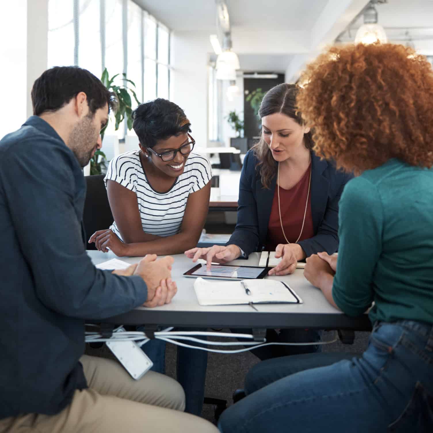 Shot of a group of colleagues working on a digital tablet at an office desk