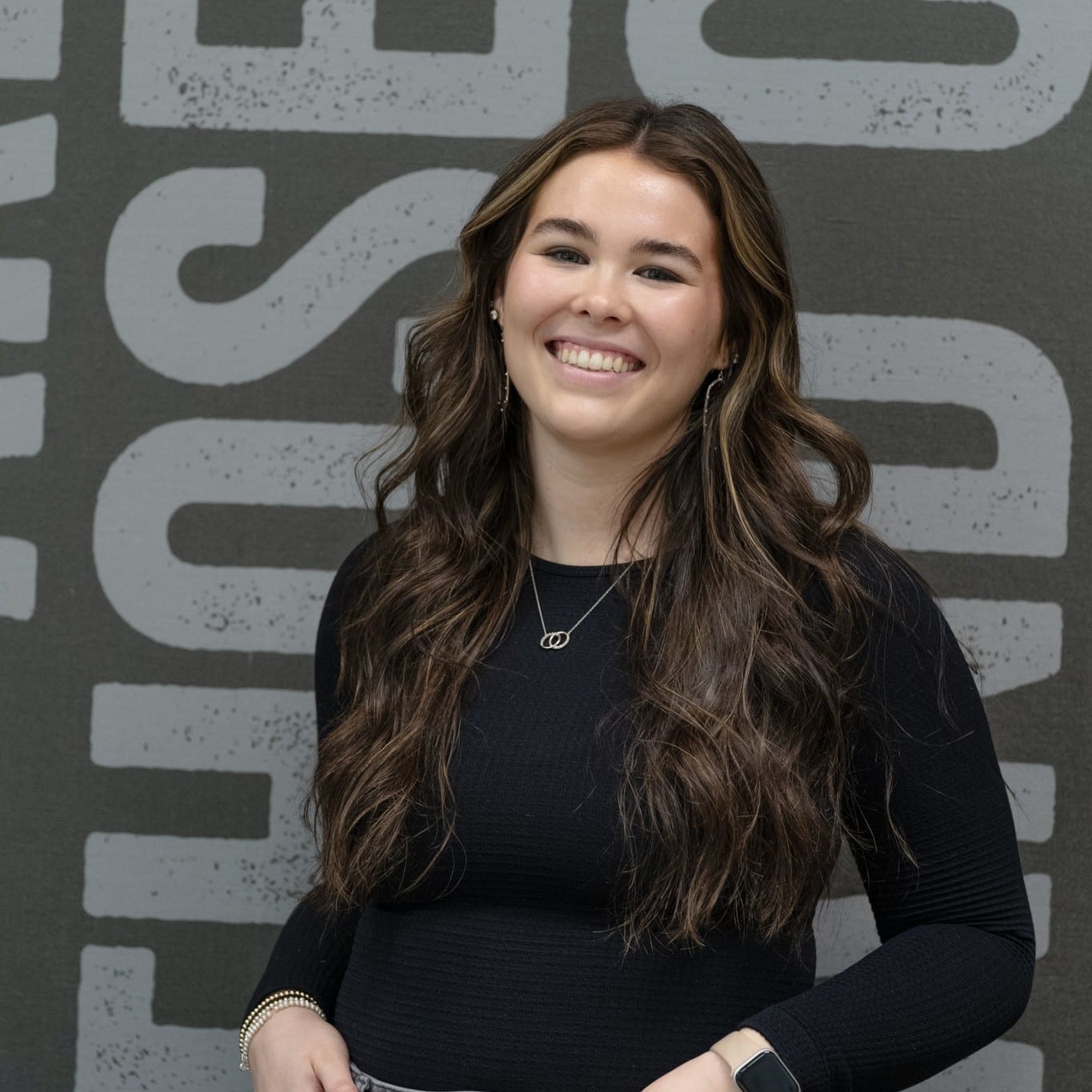 person smiling in front of wall