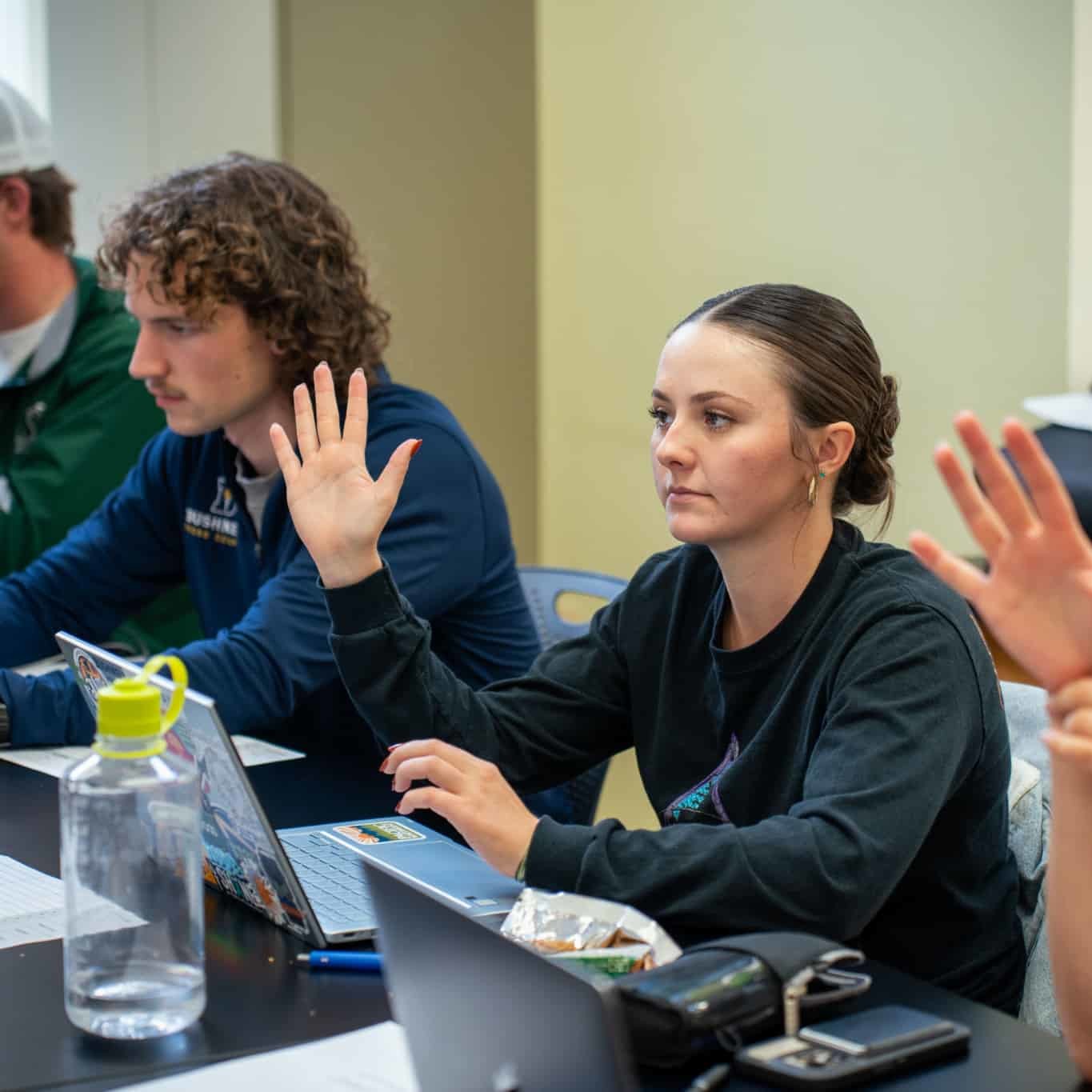 person raising their hand in class