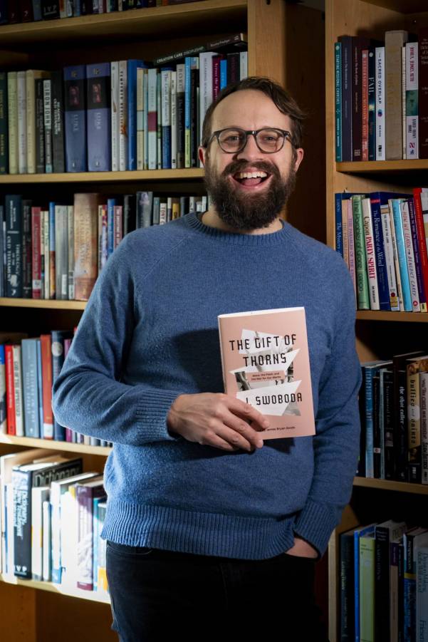person holding a book in front of a bookcase