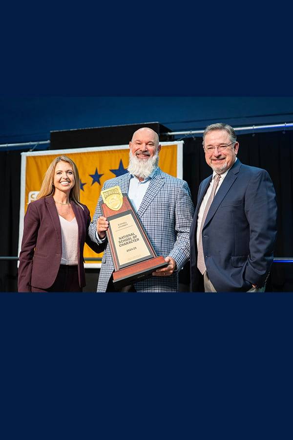 Group of people standing on stage holding trophy