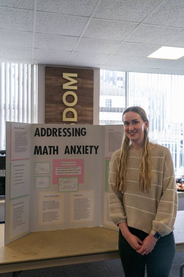 Female student standing by posterboard 